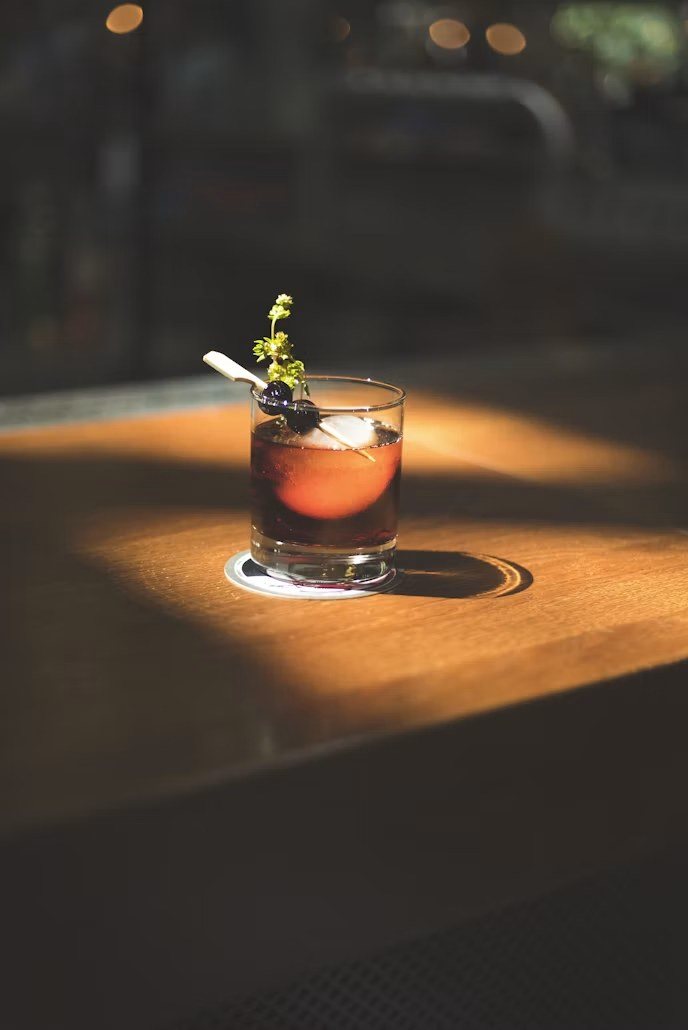 An old fashioned cocktail with an orange garnish on a wooden bar
